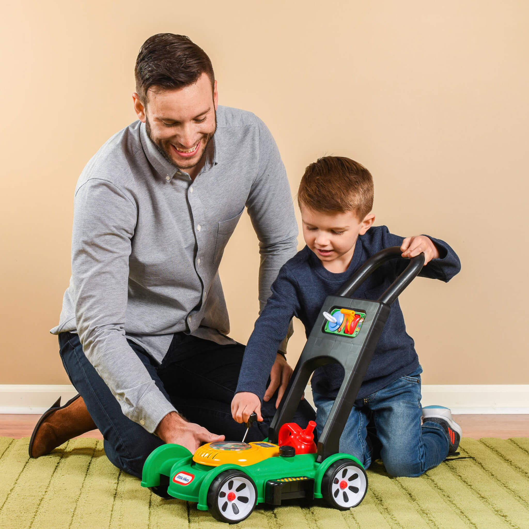 Father and son playing with toy lawn mower